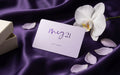 MEG 21 Gift Card on violet silk with a white orchid